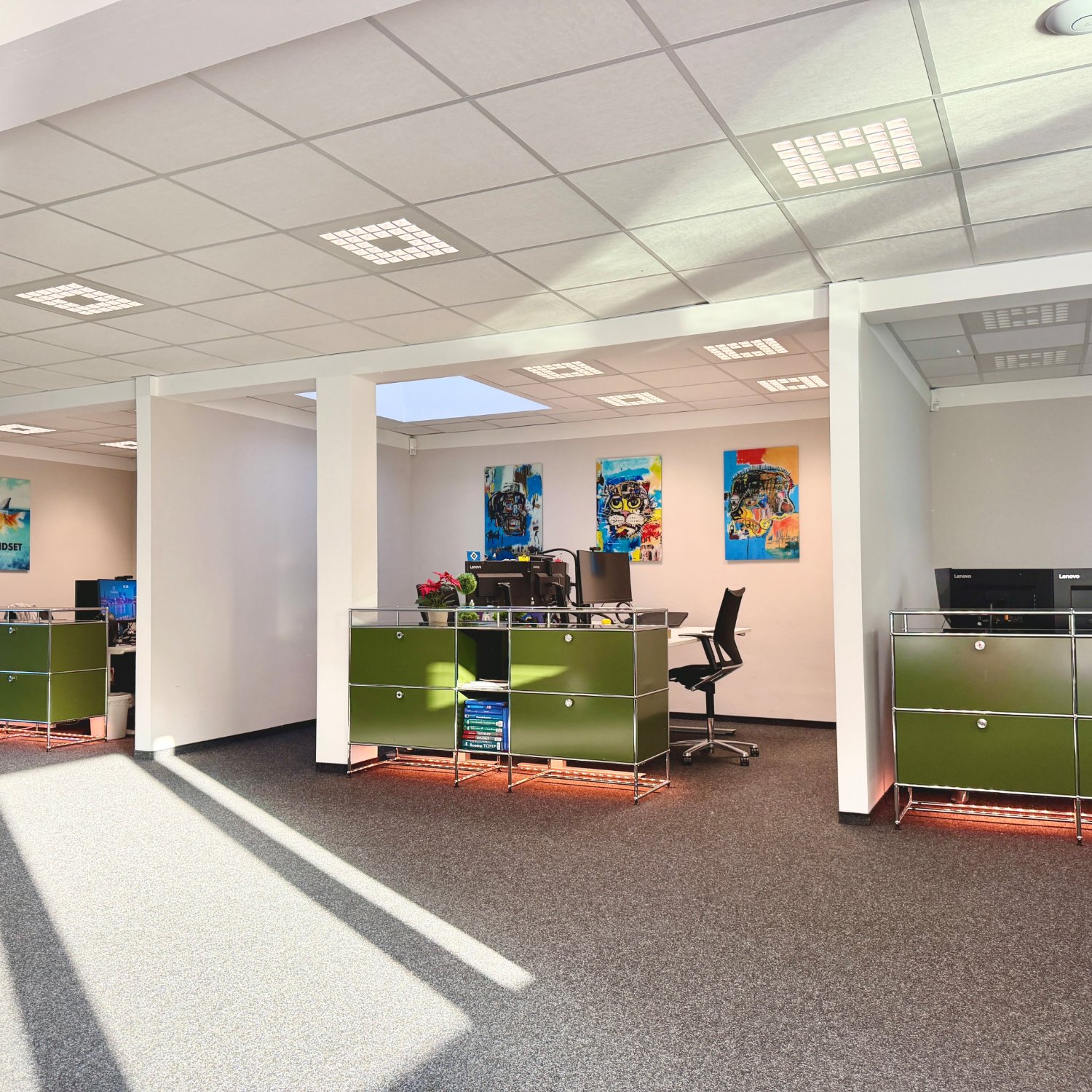 Offener Hauptraum im bTdynamics IT-Büro in Hamburg-Altona – Workstations mit Lenovo Monitoren, USM Haller Sideboards in Olivgrün und Pop-Art Kunstwerke an den Wänden