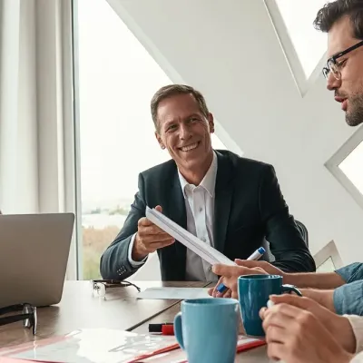 Drei Personen sitzen an einem Schreibtisch in einem modernen Büro